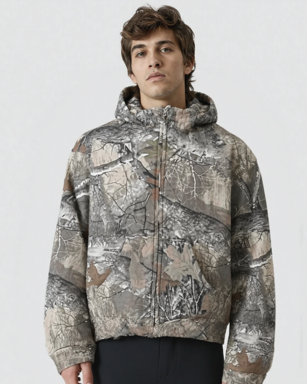 A male wearing a camouflage hoodie with a zipper
