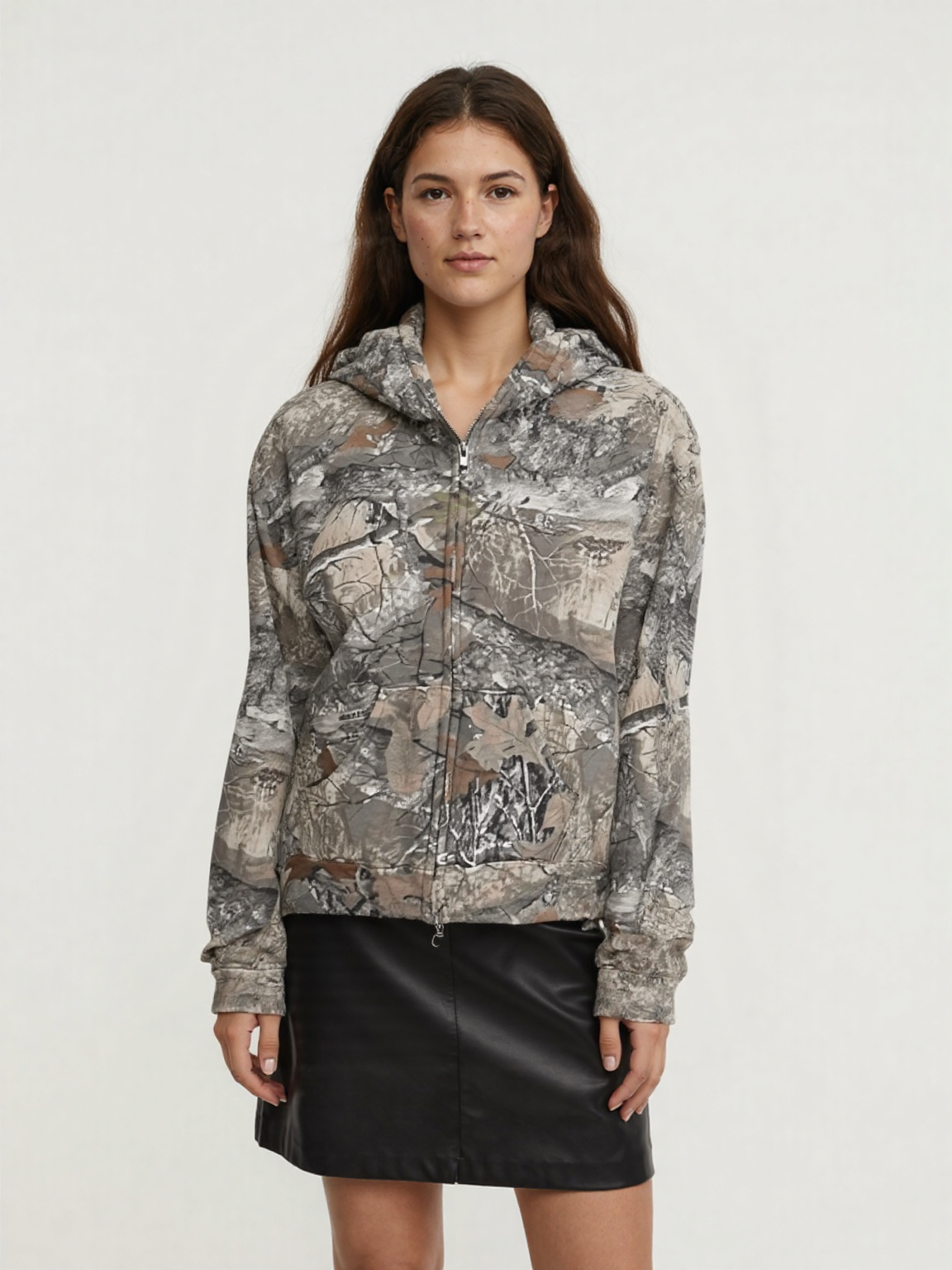 A female wearing an oversized camouflage hoodie with a zipper