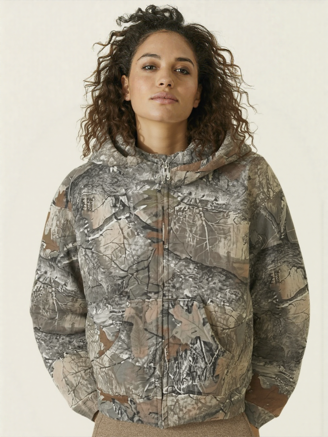 A female wearing a camouflage hoodie with a zipper